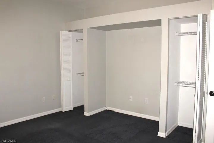Unfurnished bedroom featuring dark colored carpet and baseboards