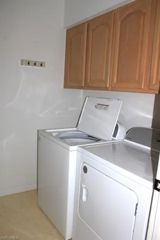 Washroom featuring washer and dryer, cabinet space, and baseboards