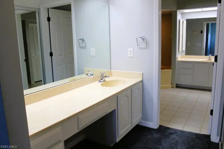 Full bathroom featuring dark tile patterned flooring, vanity, and a tub
