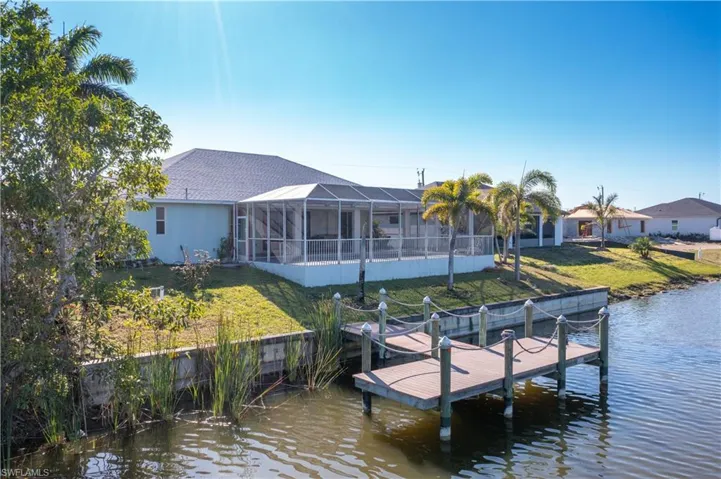 Dock area with a lawn, a sunroom, glass enclosure, and a water view