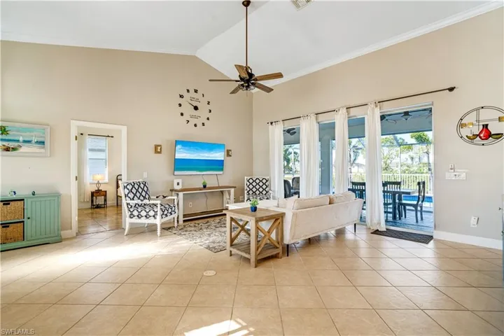 Living area featuring light tile patterned flooring, ornamental molding, high vaulted ceiling, and ceiling fan