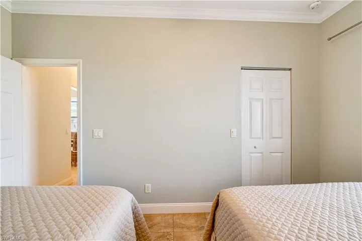 Tiled bedroom featuring ornamental molding and baseboards