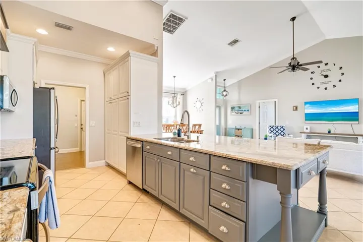 Kitchen featuring crown molding, light stone countertops, open floor plan, light tile patterned flooring, and gray cabinetry