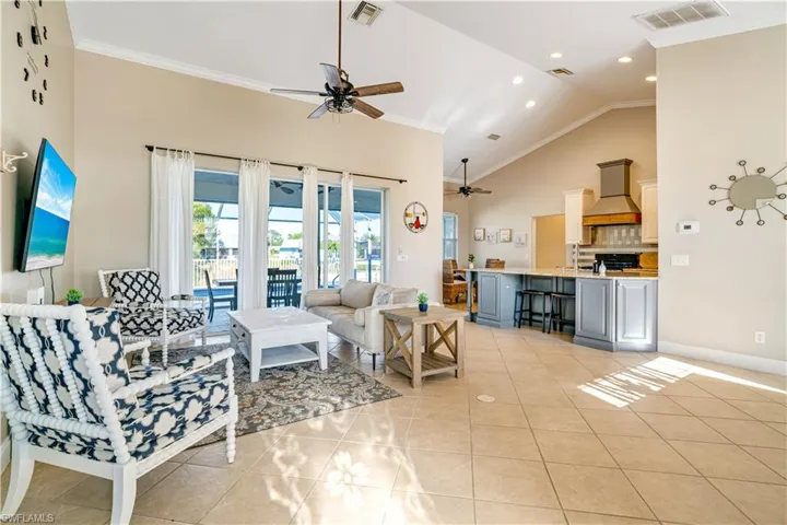 Living room featuring ornamental molding, light tile patterned floors, high vaulted ceiling, ceiling fan, and recessed lighting