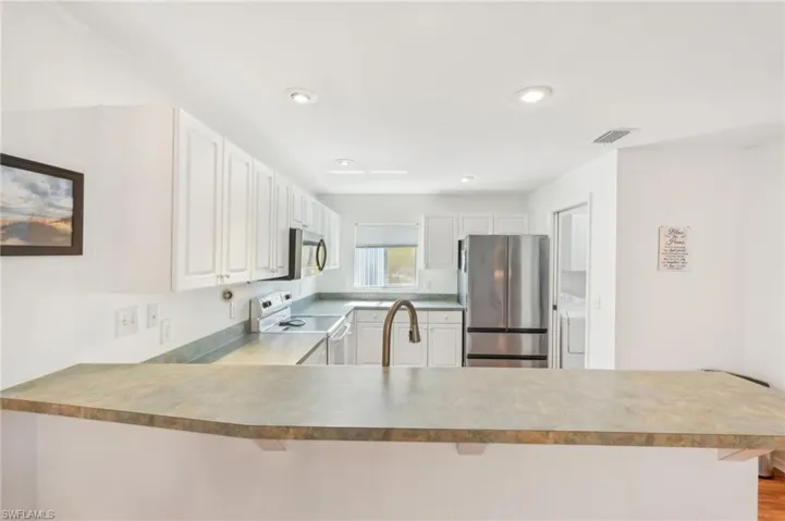 Kitchen featuring a breakfast bar area, stainless steel appliances, a sink, and a peninsula
