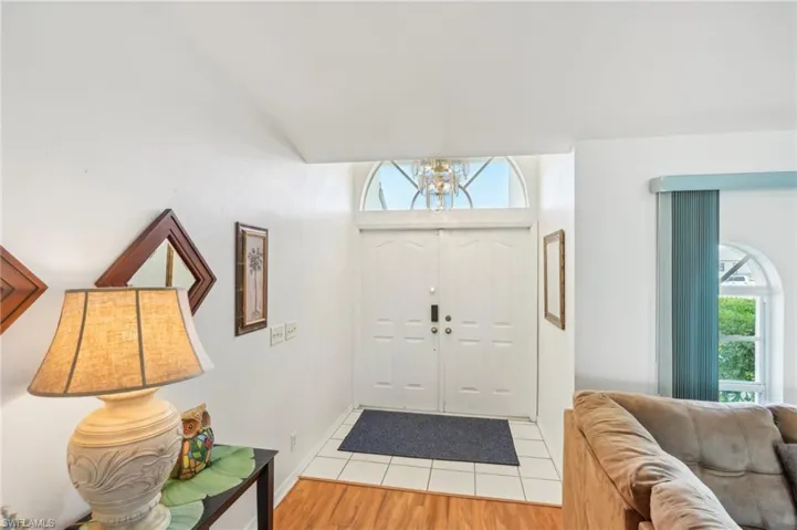 Tiled foyer featuring baseboards and a notable chandelier