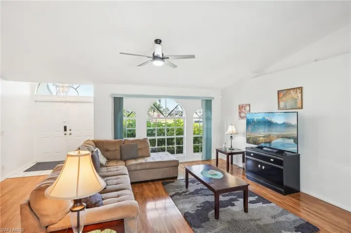 Living area with a ceiling fan, baseboards, vaulted ceiling, and wood finished floors
