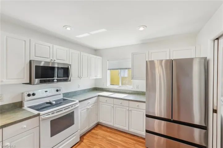 Kitchen featuring light wood-type flooring, recessed lighting, appliances with stainless steel finishes, and white cabinets