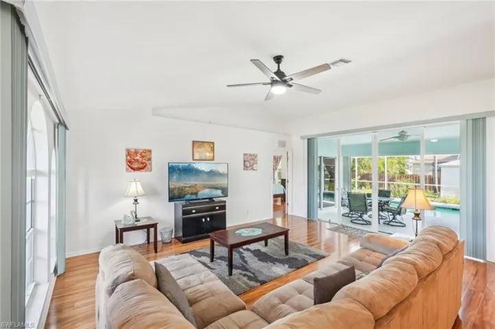 Living area featuring visible vents, a ceiling fan, lofted ceiling, and light wood-type flooring