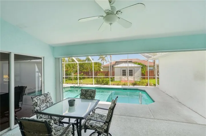 View of pool featuring an outdoor structure, ceiling fan, a patio area, and fence