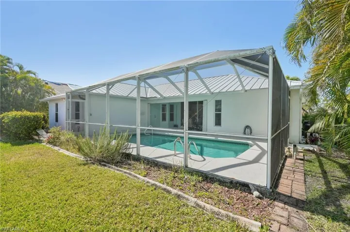 Back of property with a lanai, an outdoor pool, a yard, a patio, and stucco siding
