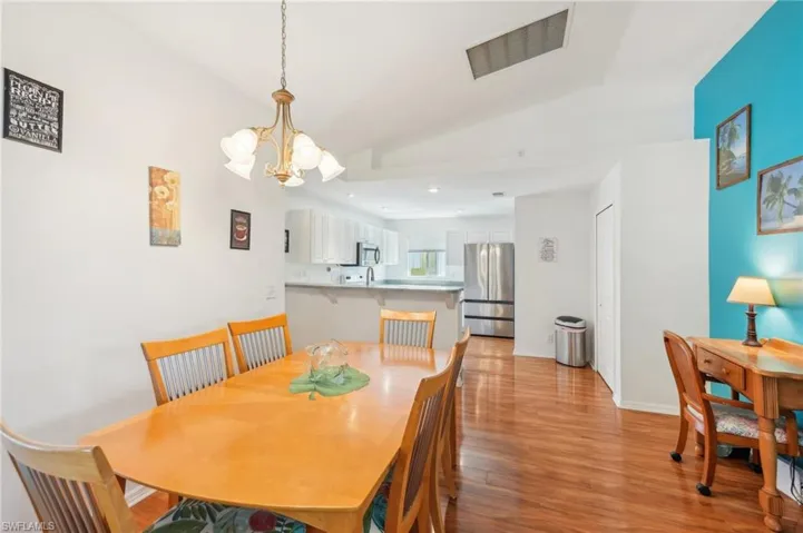 Dining space with visible vents, lofted ceiling, baseboards, a chandelier, and light wood-style flooring