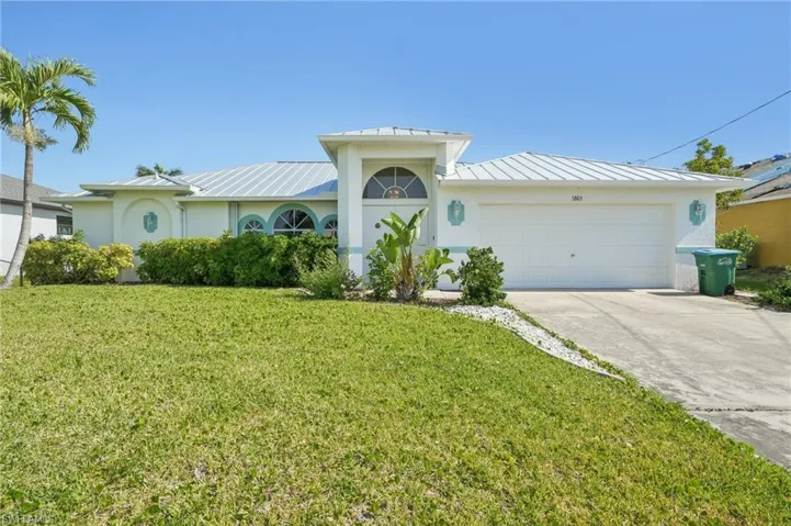 Ranch-style home featuring a garage, a front yard, stucco siding, a standing seam roof, and metal roof