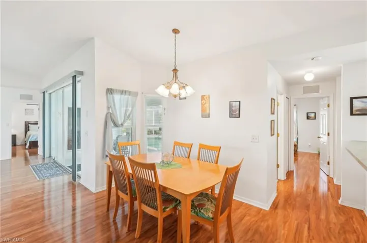 Dining room featuring visible vents, light wood-style flooring, baseboards, and a notable chandelier