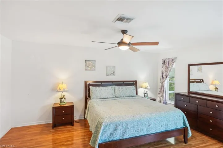 Bedroom featuring visible vents, a ceiling fan, baseboards, and wood finished floors