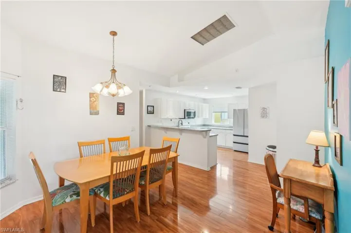Dining area with a notable chandelier, lofted ceiling, and light wood finished floors