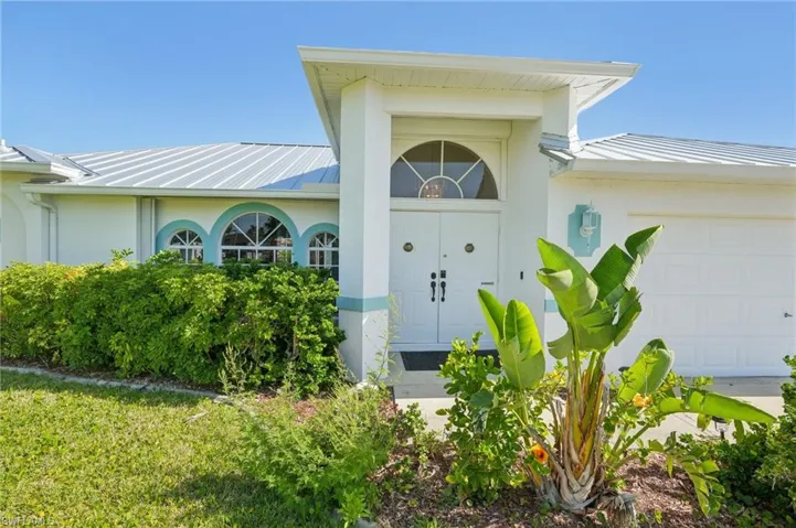 Entrance to property with an attached garage, a standing seam roof, metal roof, and stucco siding