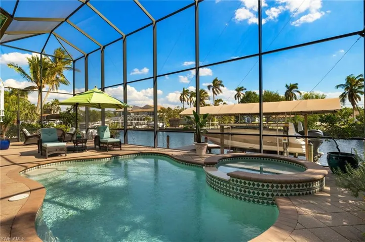 View of pool with a water view, a pool with connected hot tub, a lanai, and a patio area