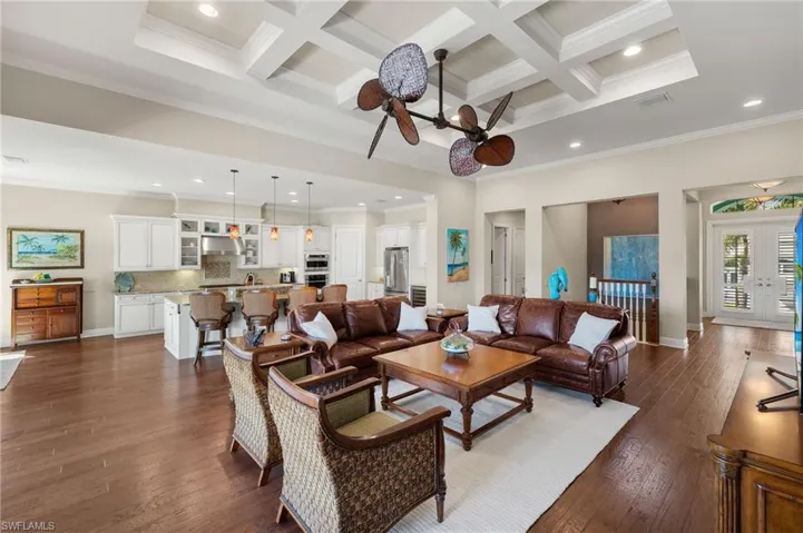 Living area featuring coffered ceiling, dark wood-style floors, crown molding, and a towering ceiling