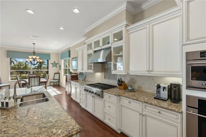 Kitchen featuring ornamental molding, appliances with stainless steel finishes, under cabinet range hood, a sink, and backsplash
