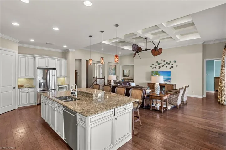 Kitchen featuring a sink, stainless steel appliances, coffered ceiling, and dark wood finished floors