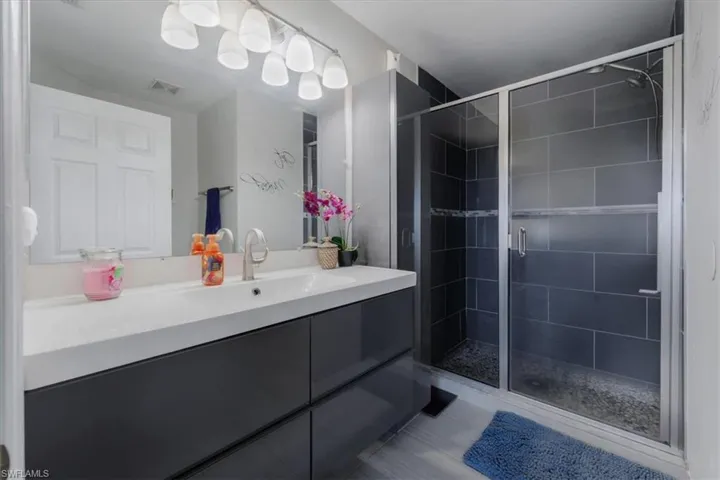 Bathroom with a shower with shower door, vanity, and tile patterned flooring