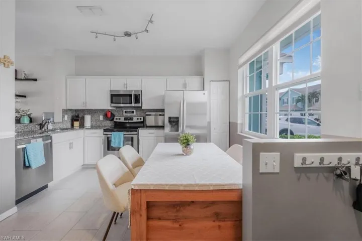Kitchen with appliances with stainless steel finishes, white cabinets, tasteful backsplash, and a healthy amount of sunlight