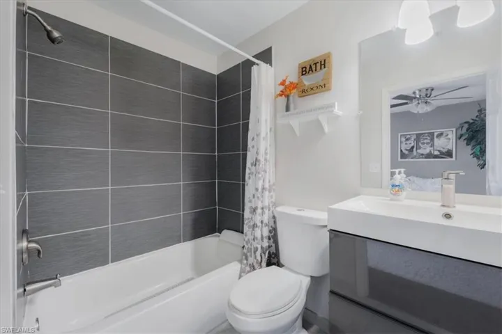 Full bathroom featuring shower / bath combo, vanity, ceiling fan, and toilet