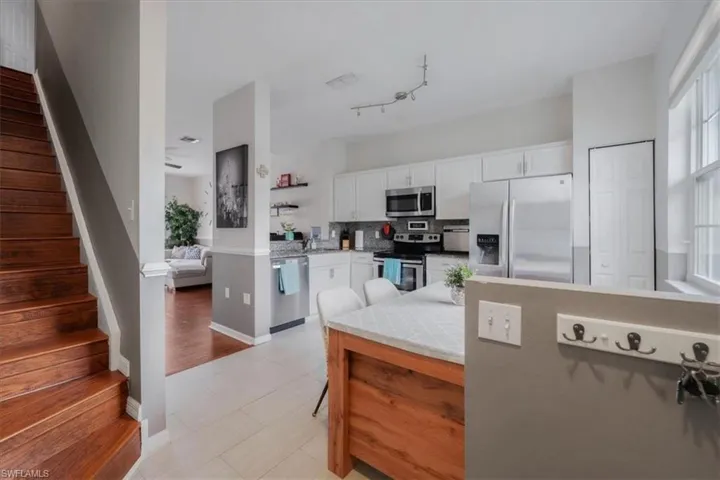 Kitchen featuring light hardwood / wood-style flooring, white cabinetry, appliances with stainless steel finishes, rail lighting, and backsplash