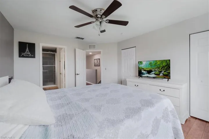 Bedroom featuring ceiling fan, ensuite bath, and light hardwood / wood-style floors