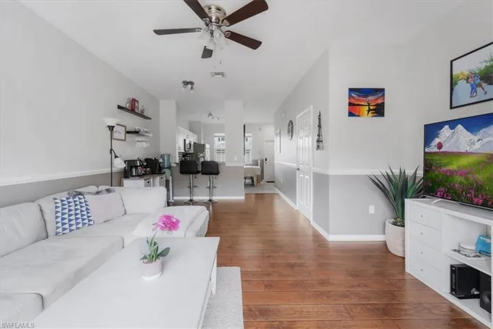 Living room with ceiling fan and hardwood / wood-style flooring