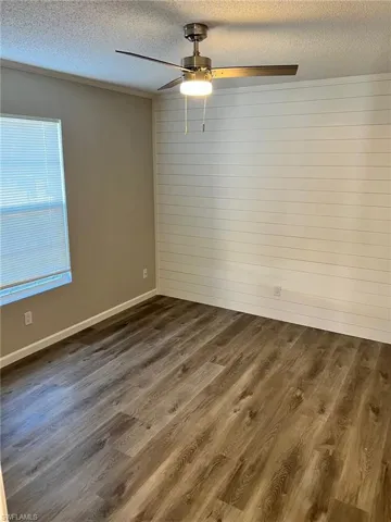 Spare room with a textured ceiling, ceiling fan, and dark wood-type flooring