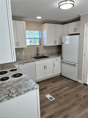 Kitchen featuring sink, white cabinets, dark hardwood / wood-style floors, and white appliances