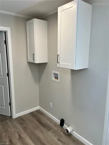 Laundry room with cabinets, washer hookup, a textured ceiling, crown molding, and dark wood-type flooring