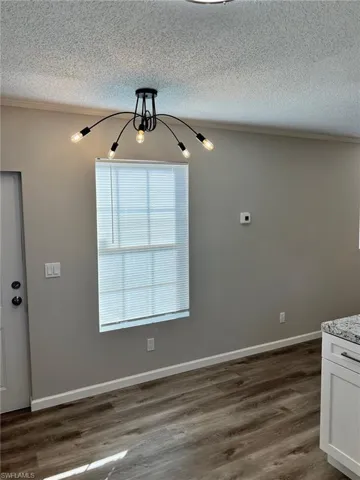 Unfurnished dining area featuring a notable chandelier, dark hardwood / wood-style floors, and a textured ceiling