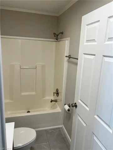 Bathroom with bathing tub / shower combination, toilet, and ornamental molding