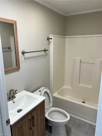 Full bathroom featuring ornamental molding, vanity, shower / washtub combination, tile patterned flooring, and toilet