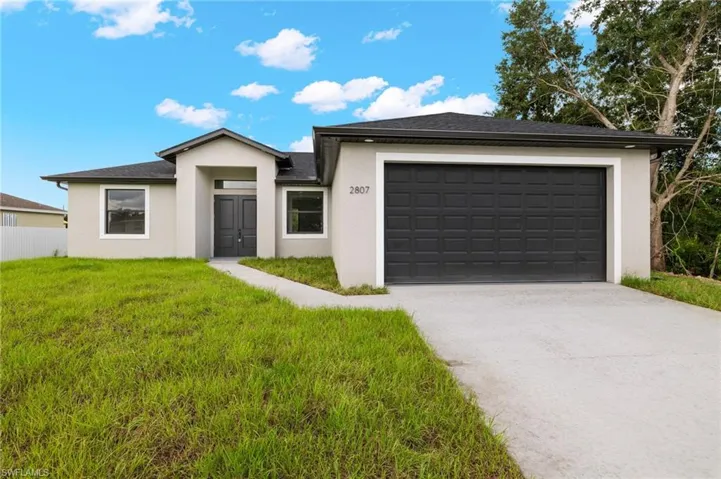 View of front of house featuring a garage and a front lawn