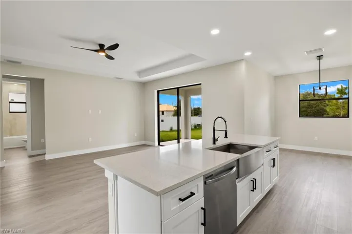 Kitchen with white cabinetry, light wood-type flooring, ceiling fan, stainless steel dishwasher, and sink