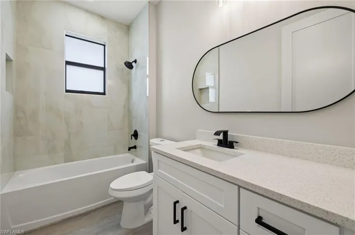 Full bathroom featuring wood-type flooring, tiled shower / bath, vanity, and toilet