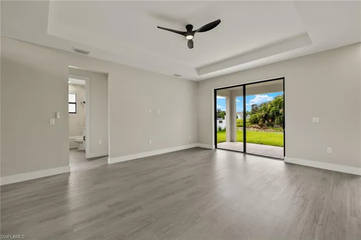 Unfurnished room featuring ceiling fan, a tray ceiling, and hardwood / wood-style floors