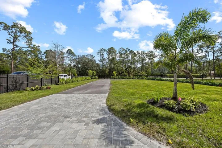House is set back from the road with beautifully landscaped driveway and fenced yard