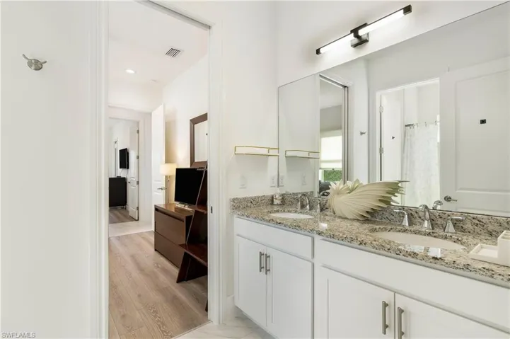 Bathroom featuring double vanity, a shower with curtain, and light wood-style flooring