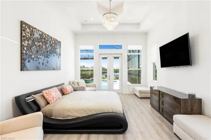 Bedroom featuring access to outside, wood finished floors, french doors, a chandelier, and a high ceiling