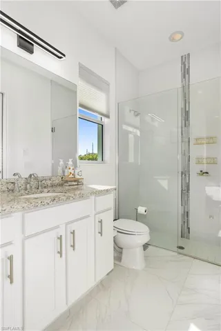 Bathroom with vanity, a shower stall, and light marble finish flooring
