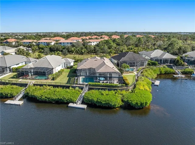 Aerial view of residential area featuring a large body of water and a tree filled landscape