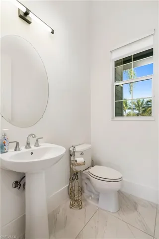 Half bath featuring marble finish flooring and baseboards