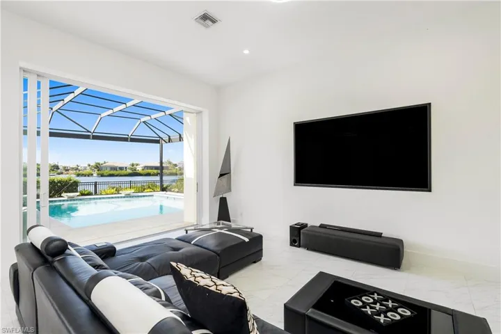 Living area featuring a sunroom, light marble finish flooring, and recessed lighting