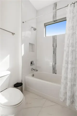 Full bathroom featuring shower / bathtub combination with curtain and marble look tile flooring