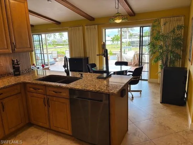 Kitchen featuring black dishwasher, a peninsula, brown cabinetry, and a sink